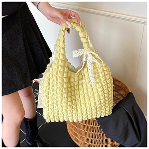 Detail of light yellow popcorn texture handbag with a white lace bow detail