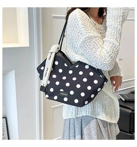 Detail of canvas bucket bag with large white polka dots and fashion logo leather patch