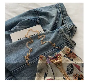 Detail of vintage floral woven bucket bag with gold chain strap and metal drawstring buckle