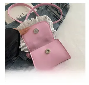 Detail of pink crossbody bag with lace trim showing dual magnetic cylinder buckles