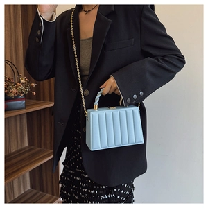 Detailed view of light blue wavy textured handbag with gold chain on display