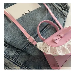 Pink mini crossbody bag with cute bow detail and white crochet lace edges on denim