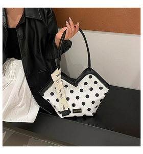 Detail of white polka dot bucket bag with V-shaped opening and woven logo strap