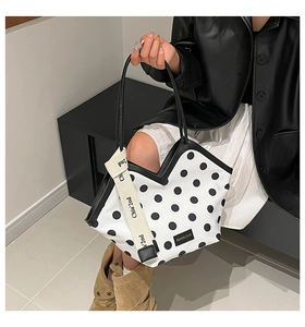 Detail of black and white polka dot tote bag with stylish fabric strap and fashion label
