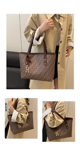 Detail of a brown tote bag with letter prints, dark handles and a golden R pendant