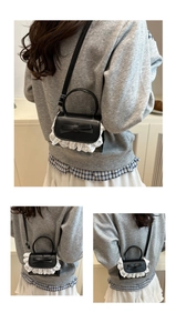 Dettaglio mini borsa a tracolla in pelle PU nera con pizzo bianco e fiocco decorativo