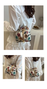 Detail of floral tapestry bucket bag featuring gold chain strap and pearl drawstring