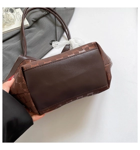 Gros plan sur un sac cabas en jacquard marron avec logo et nœud décoratif en dentelle