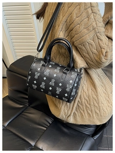 Detail of black cylindrical boston bag with white bear print and textured leather