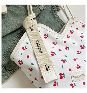 Detail of cherry pattern tote with heart-shaped V-cut and stylish fabric wide strap