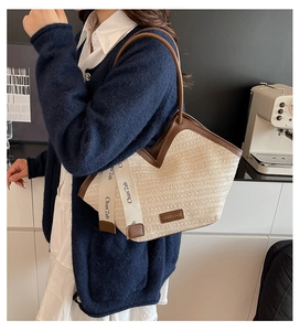 Detail of straw woven tote bag with brown leather trim and stylish logo ribbon detail