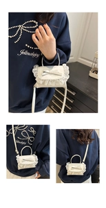 Dettaglio mini borsa bianca con bordo in pizzo e decorazione a fiocco raffinata