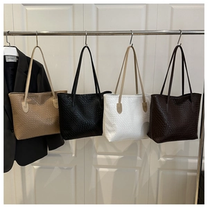 Detail view of woven texture tote bags in white, black, dark brown, and light brown colors