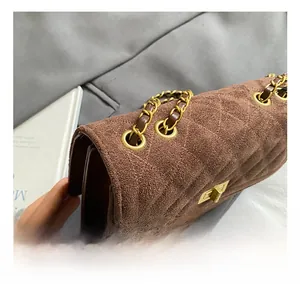 Detailed shot of brown suede crossbody bag with gold chain strap and quilted texture