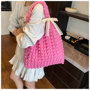 Détail du sac cabas rose en tissu gaufré avec un nœud décoratif en dentelle blanche
