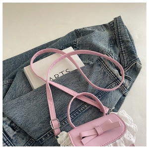 Dettaglio di mini borsa rosa con un fiocco dolce e ricami in pizzo bianco sulla base