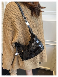 Detail of black sequin underarm bag featuring silver buckle and leather shoulder strap