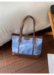 Detail of vintage denim tote bag with leather straps and reinforced brown bottom