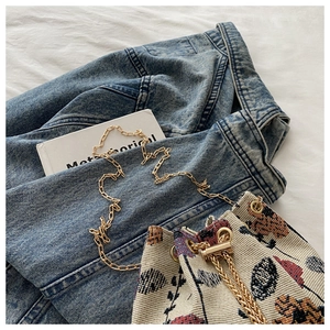 Detailed close-up of a vintage floral jacquard bucket bag with gold chain and metal drawstring