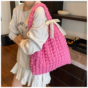 Sac fourre-tout rose à texture bulles et nœud en dentelle blanche porté par un mannequin