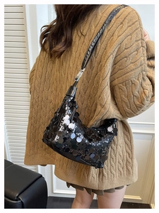 Close-up of black sequined shoulder bag on brown cable knit sweater in chic urban setting