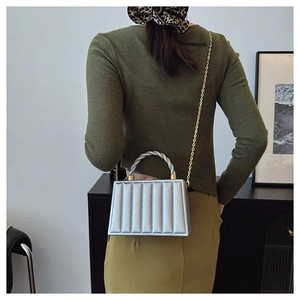 Silver structured handbag with wavy vertical stripes and metallic chain on a model