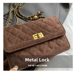 Detailed close-up of golden hardware lock and quilted suede texture on the brown shoulder bag