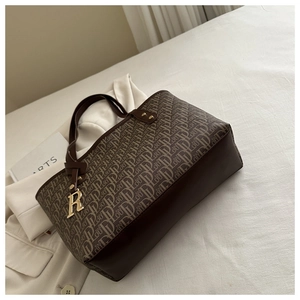 Close-up of vintage brown tote bag featuring luxury monogram canvas and gold R pendant