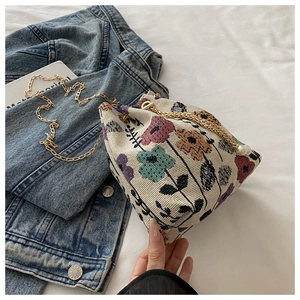 Detail of floral tapestry bucket bag featuring gold chain and pearl drawstring charms