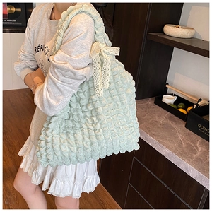 Gros plan détaillé d'un sac vert clair à texture bulles et nœud en dentelle blanche
