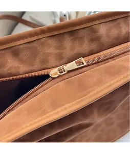 Detailed close-up of premium golden metal zipper on vintage leopard brown suede shoulder bag