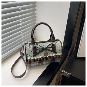 Detail of mint green cylindrical bag with star print, leather bow, and heart charm