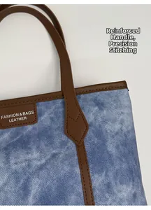 Close-up of reinforced handles and precise stitching on blue denim tote bag detail
