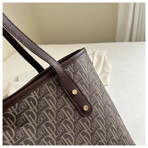 Detailed view of the monogram tote bag with brown leather handles and golden rivets