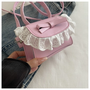 Dettaglio della mini borsa quadrata rosa con pizzo e fiocco tenuta in mano