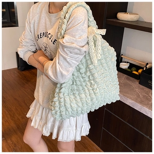 Détail du sac cabas vert clair en tissu popcorn avec nœud en dentelle blanche et texture gaufrée