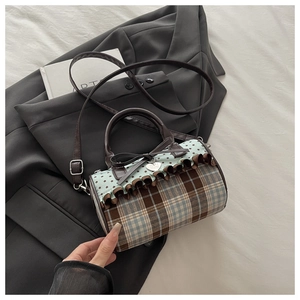 Detail of Boston style cylinder bag featuring vintage plaid, bow pendant, and ruffle trim