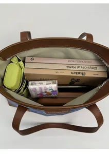 Vertical top view showing large interior capacity of blue denim tote with brown leather trim