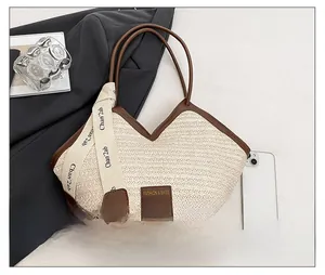 Detail of woven straw tote bag with brown leather trim and fashion label accents
