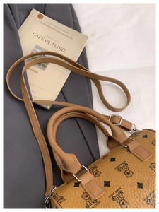 Detailed view of brown leather Boston bag with bear print and adjustable strap