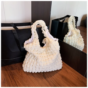 Détail du sac cabas en tissu texturé popcorn crème avec un nœud en dentelle délicat