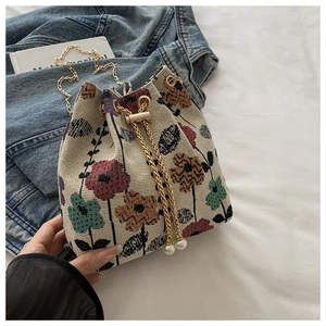 Detail of floral bucket bag with pearl pendant, gold chain strap and drawstring closure