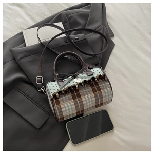 Detail of checkered mini barrel bag with ruffle trim and heart pendant on a blazer