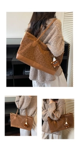 Detail of leopard print tote bag with brown leather handles and a plush bear charm