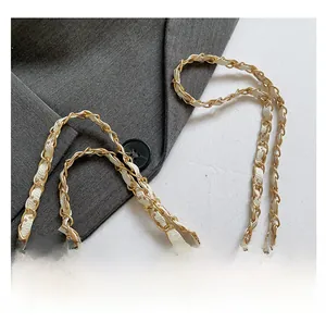 Detail of light gold metal chain strap woven with beige vintage patterned leather