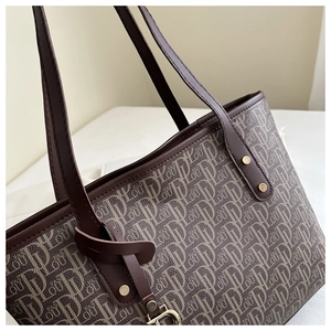 Detail of vintage monogram canvas tote bag with brown leather trim and metal charm