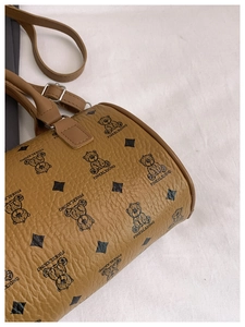 Detailed close-up of pebble-textured brown Boston bag featuring bear and crown patterns