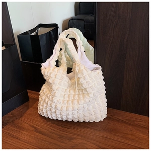 Détail du sac cabas blanc à texture gaufrée montrant le tissu matelassé sur bois