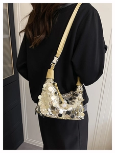 Close-up of sparkling gold and silver sequins on a stylish underarm bag with leather strap