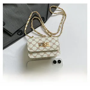 Mini crossbody bag with vintage monogram pattern shown next to a smartphone for size reference